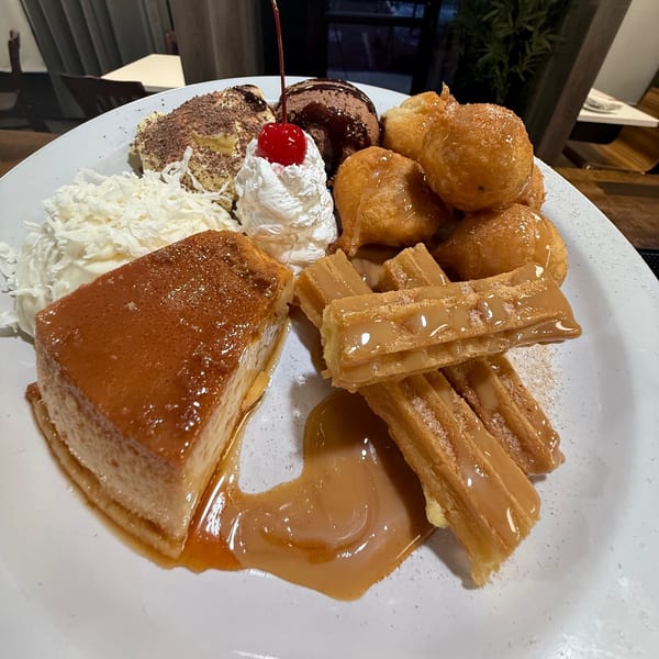 Aroma do Brazil dessert platter with flan, churros, fried dough, ice cream, whipped cream, and coconut flakes.