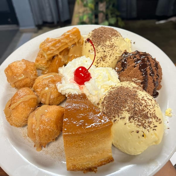 A Brazilian dessert platter with flan, fried dough, ice cream, whipped cream, and a cherry.