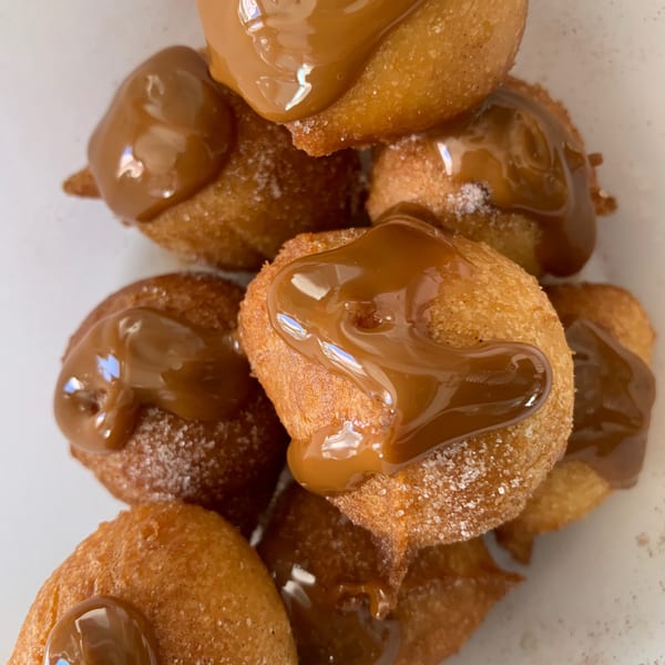 Close-up of golden-brown Brazilian churros, dusted with sugar and drizzled with dulce de leche.