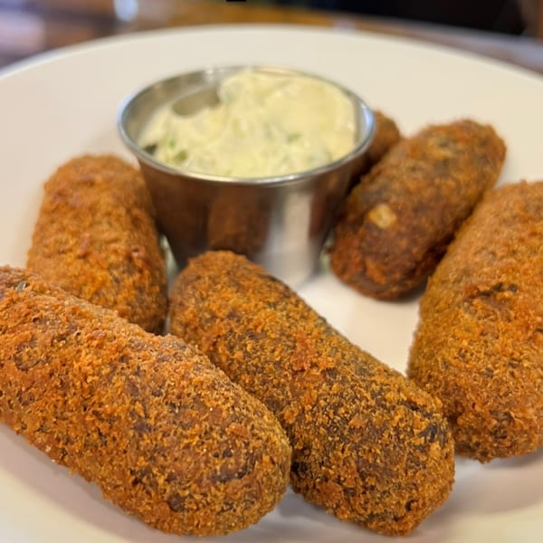 Aroma do Brazil's Brazilian croquettes, golden-brown and crispy, served with a creamy green dipping sauce.